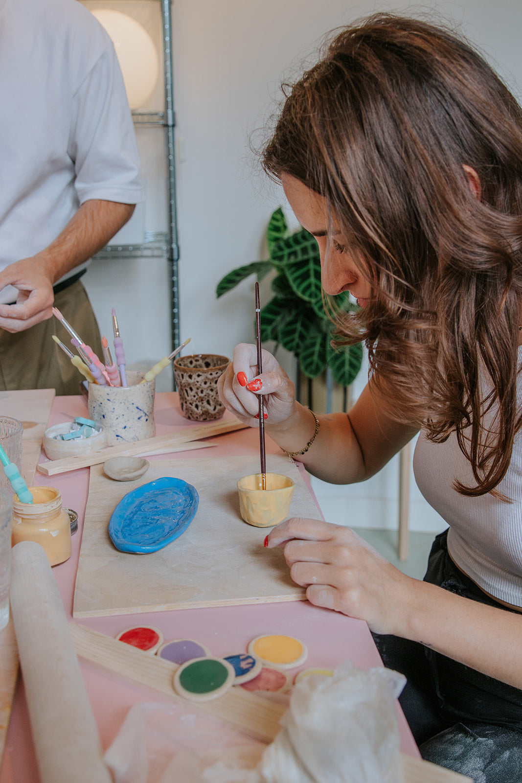Deelnemers glazuren hun keramiek tijdens een make and paint workshop