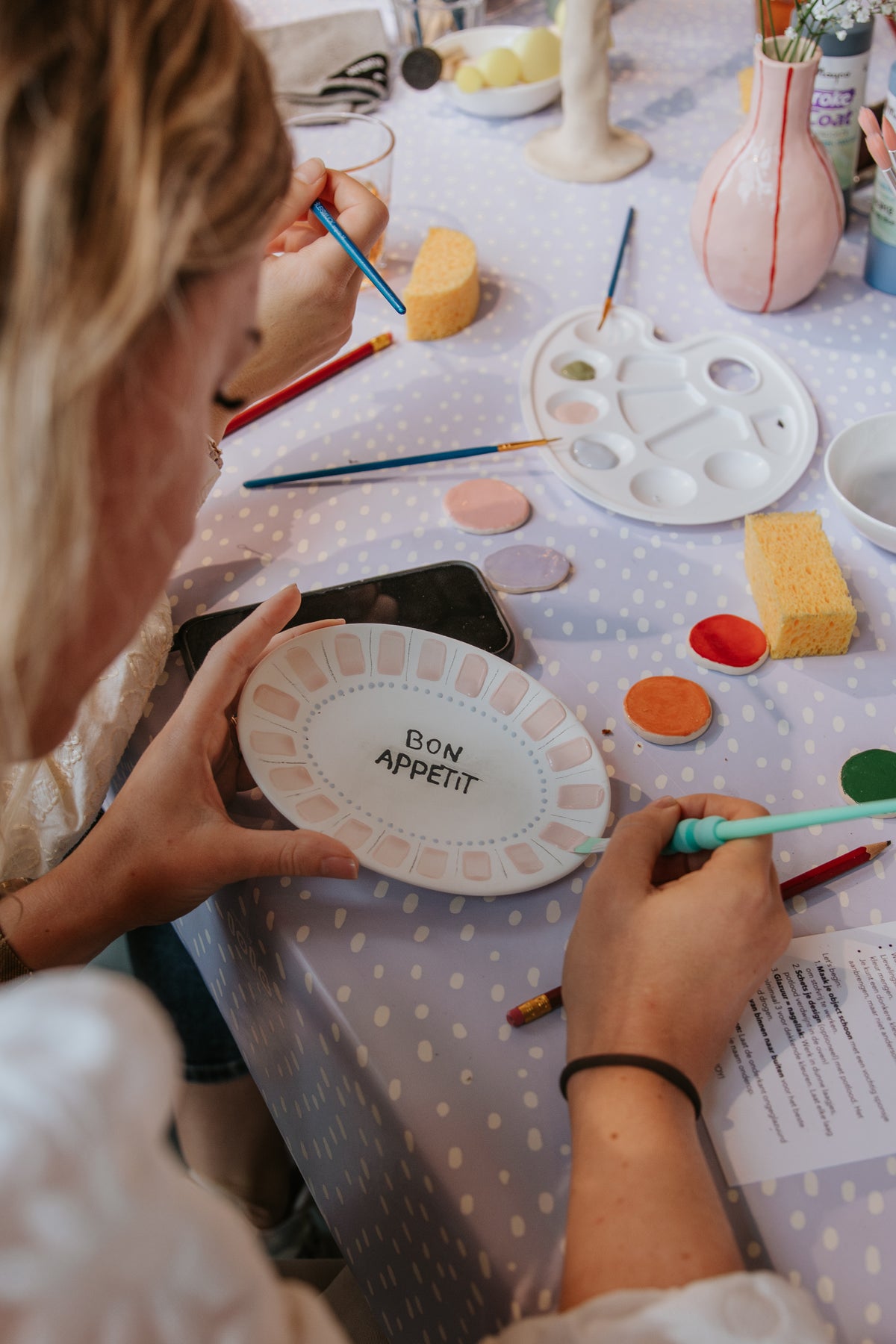 Bord beschilderen met de tekst Bon Appetit tijdens keramiek schilderen