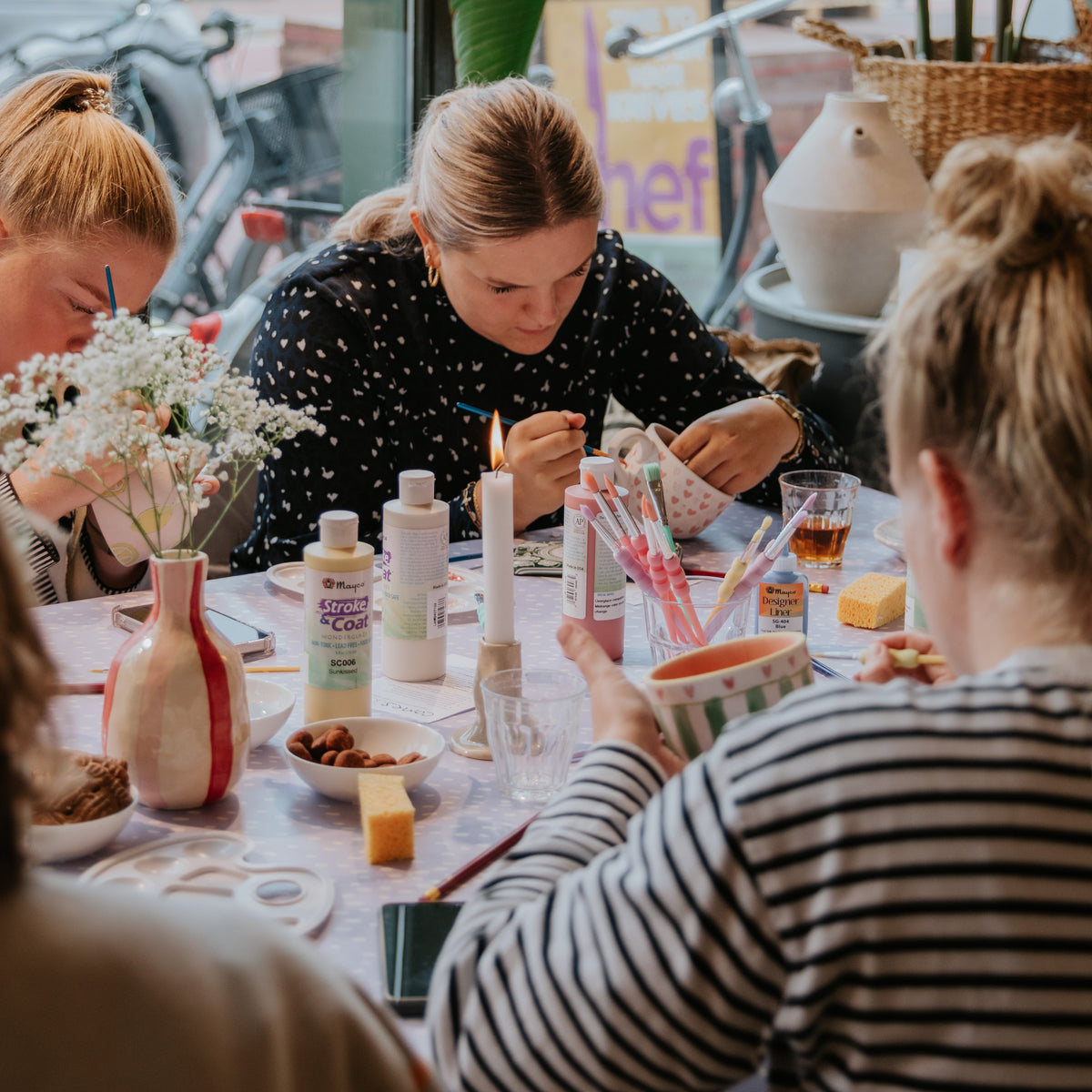Vriendinnen aan tafel tijdens een keramiek schilderen workshop